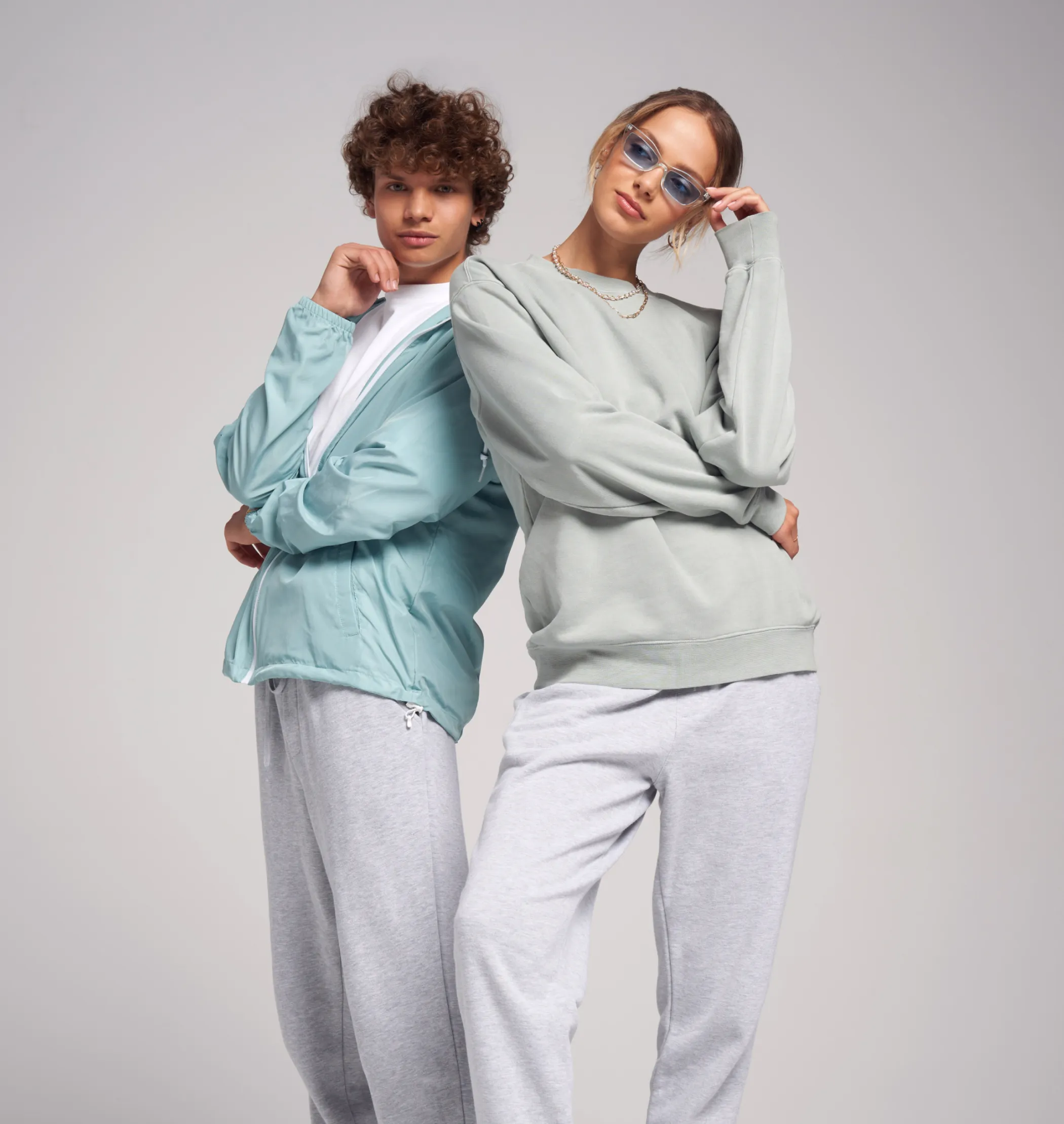 A male and a female model with sweatpants and sweatshirts on. Displaying two products that can be created on Fourthwall