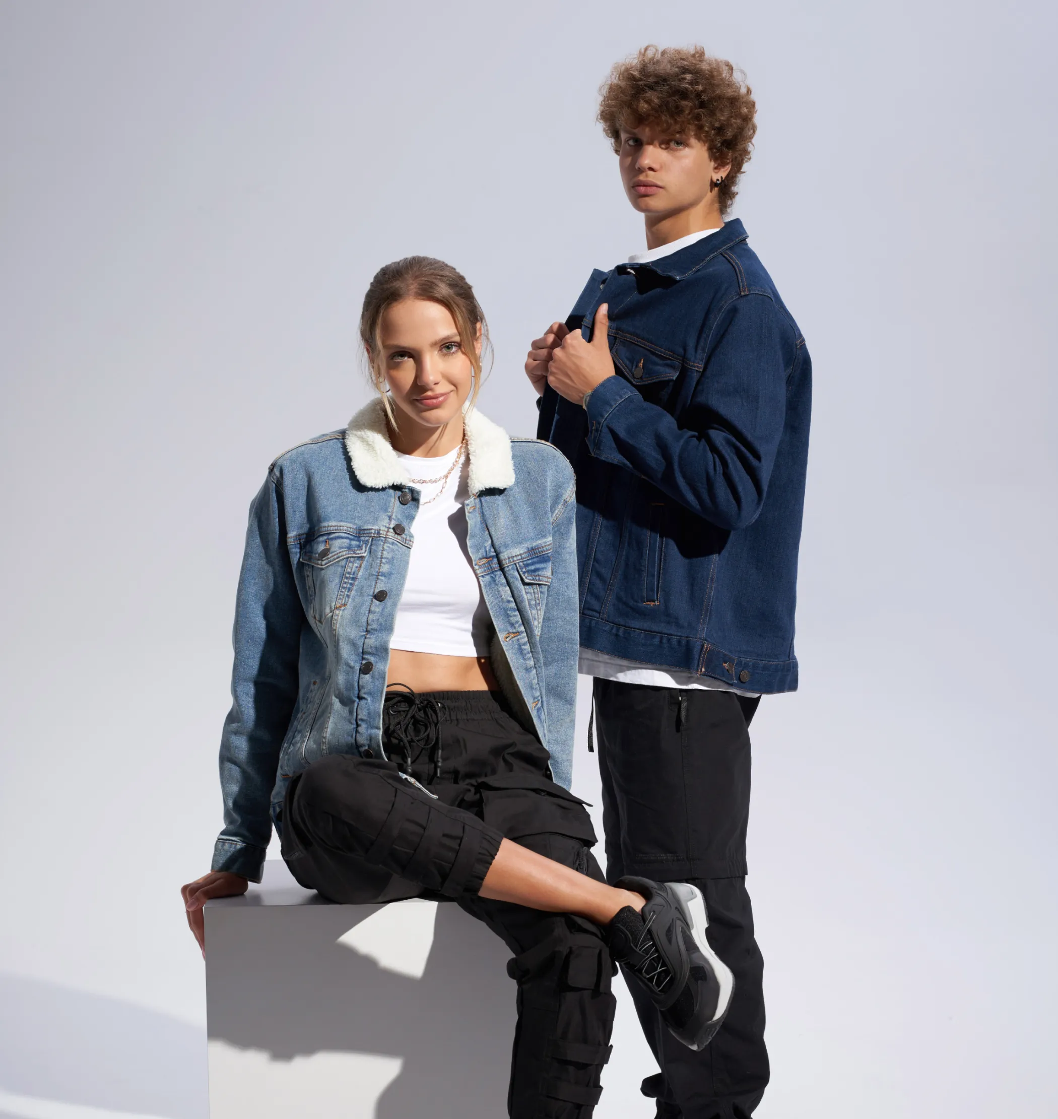 A male and female model wearing denim jackets that are available to design using Fourthwall